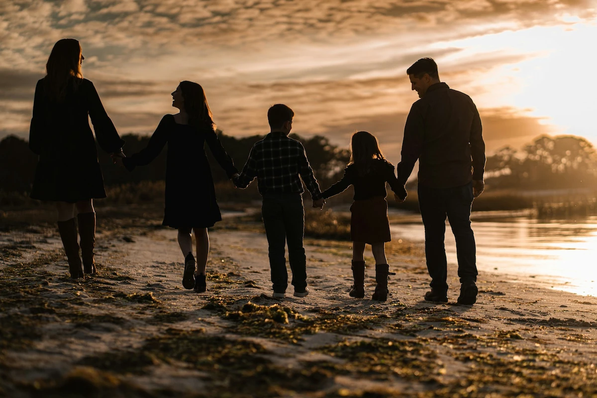 famille marchant sur la plage au coucher de soleil