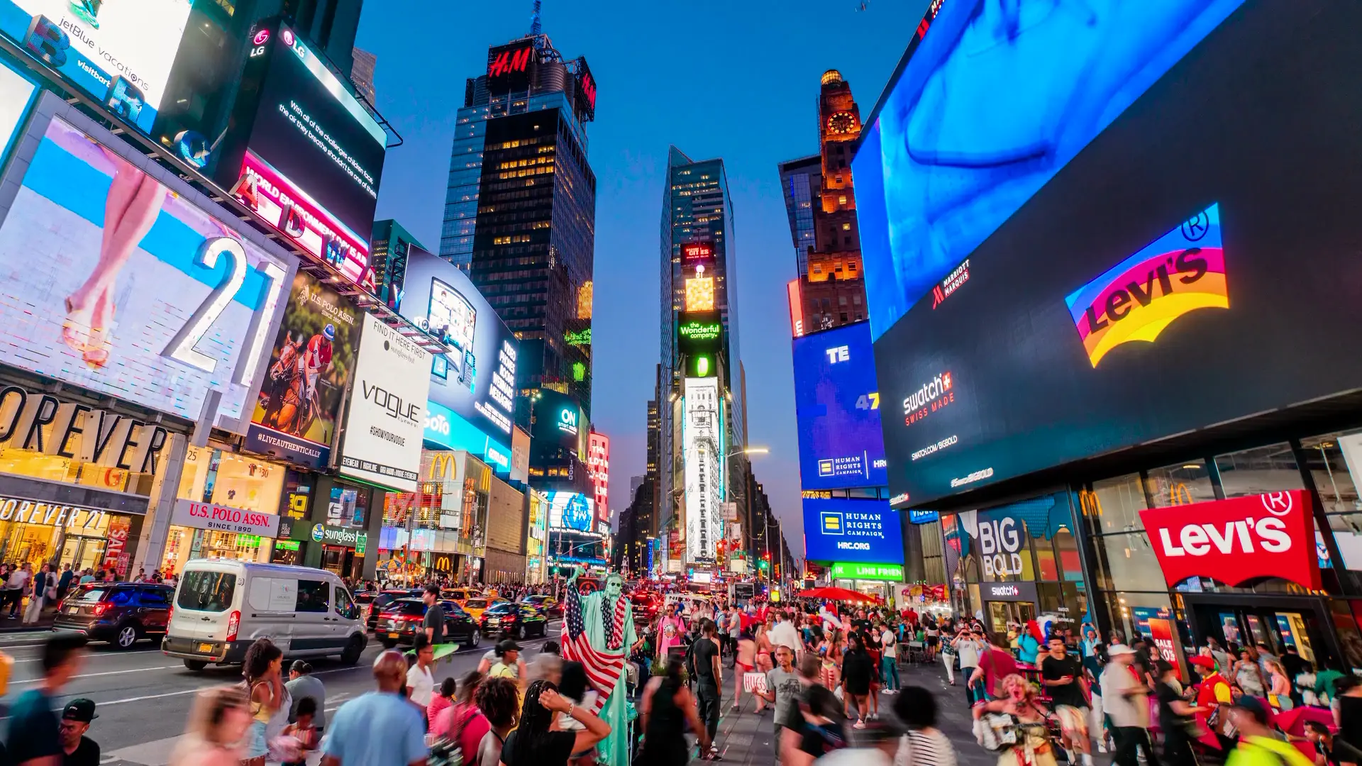 La place Times Square à New-York, lors de la tombée de la nuit, avec beaucoup de monde circulant
