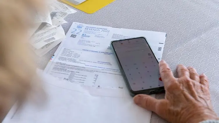 Personne âgée calculant ses impôts, téléphone, feuille de déclaration d'imposition 2022
