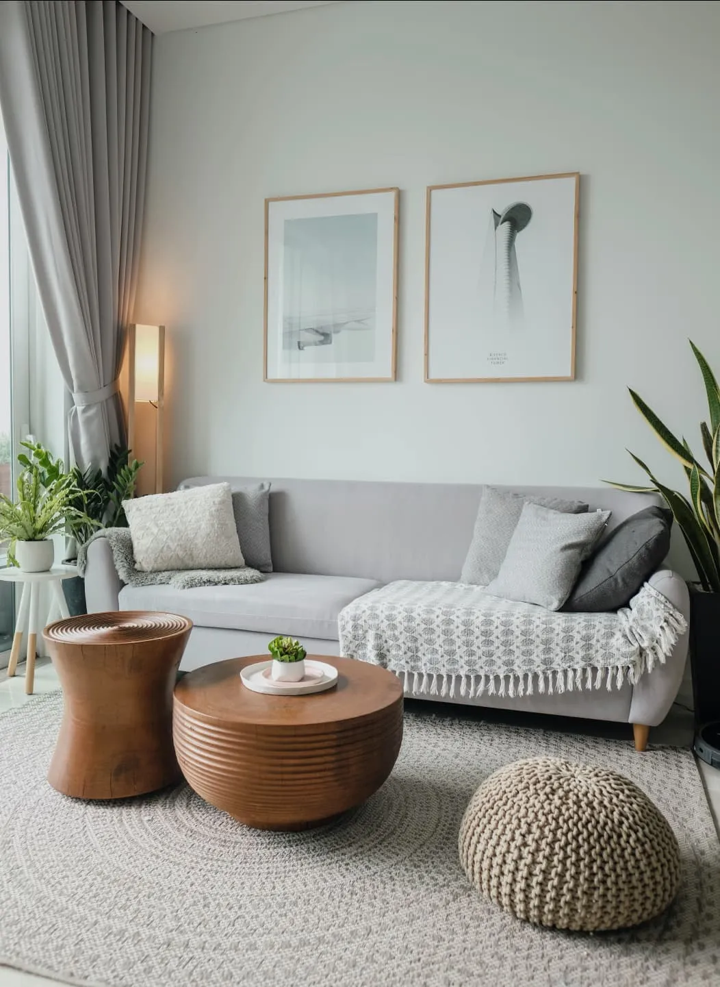 Un salon confortable un canapé, des poufs, et des tableaux sur un mur blanc