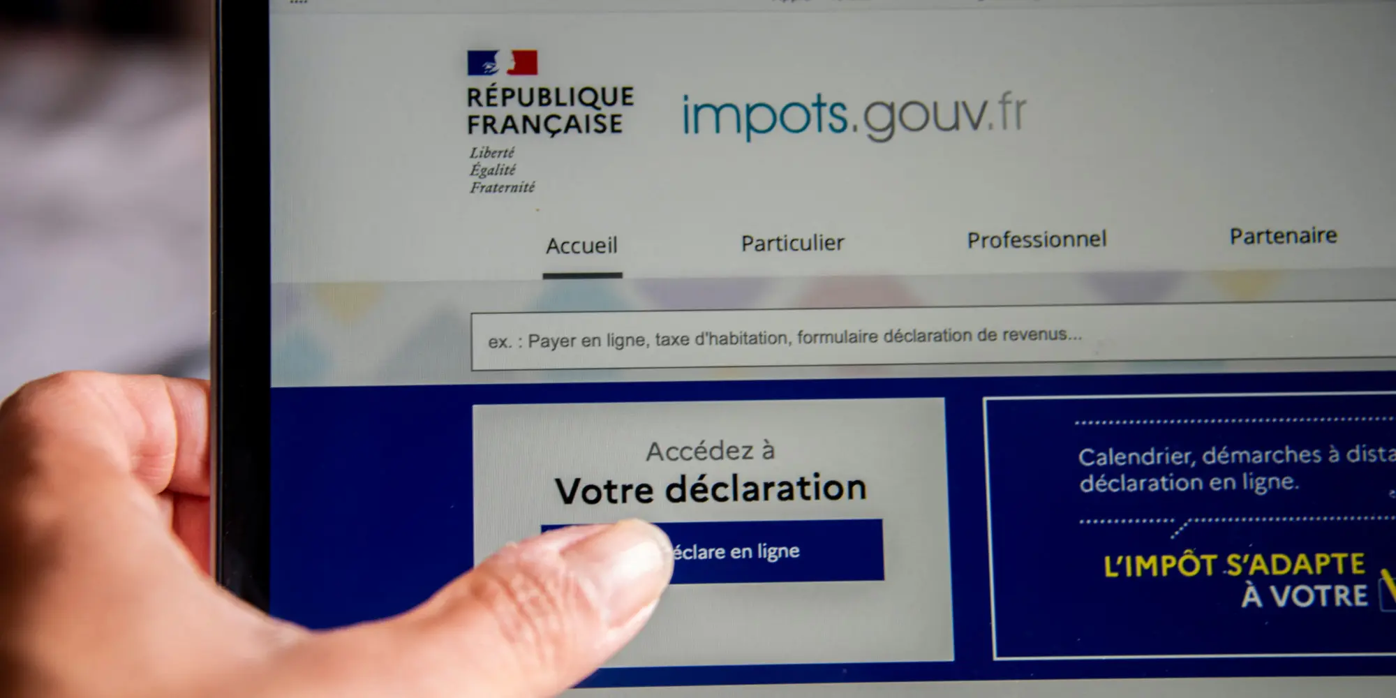 Site impots.gouv.fr affiché sur un écran, femme déclarant ses impôts